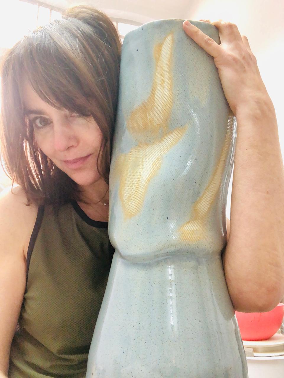 Karine Letayf tenant un grand vase bleu-gris et ocre