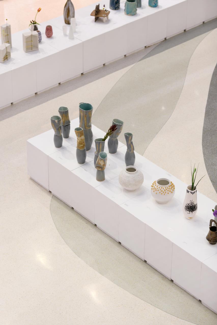 Vue de l'exposition et des vases sur leurs socles blancs