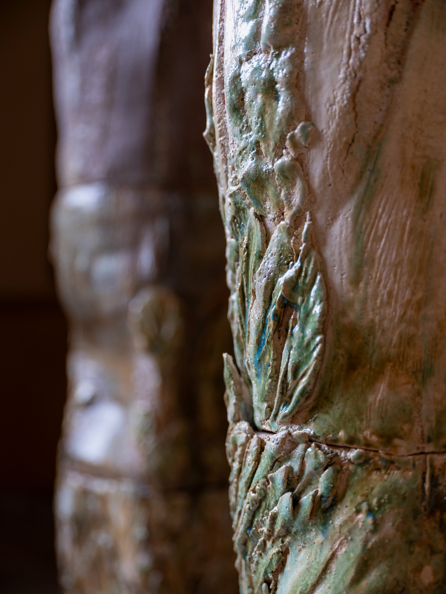 Détail de surface d'un totem en grès, émail vert et bleu sur terre claire